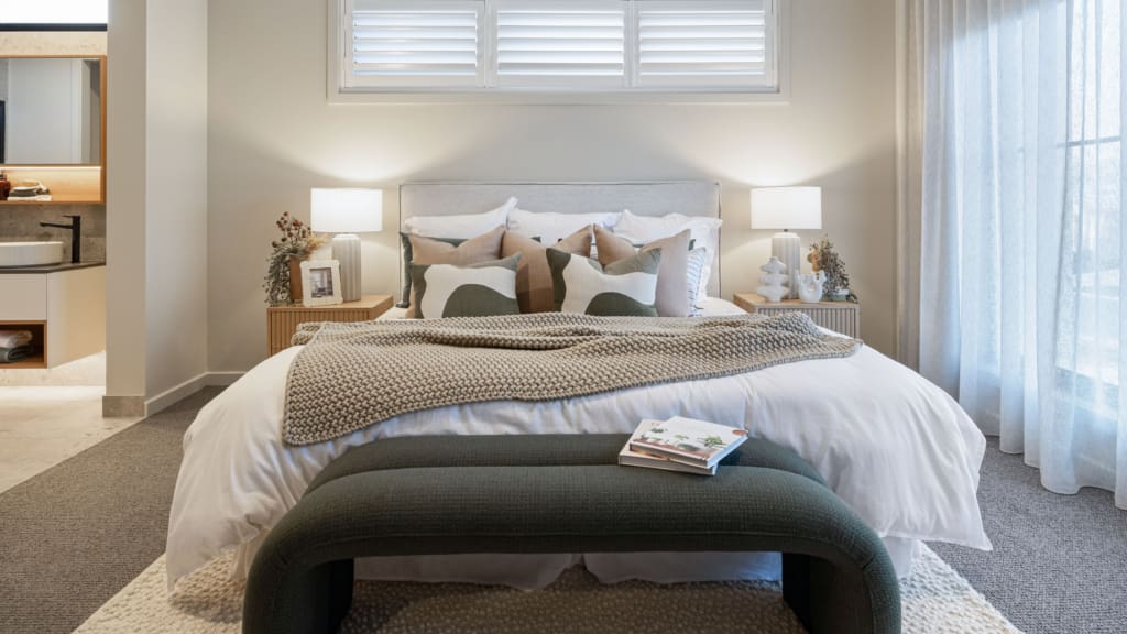 Stylish bedroom with layered pillows, knit throw, and bedside lamps | Davis Sanders