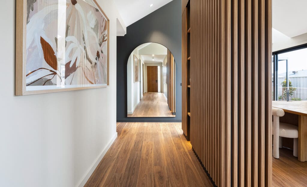 Home hallway with wood floor, slatted wood paneling, and mirror | Davis Sanders